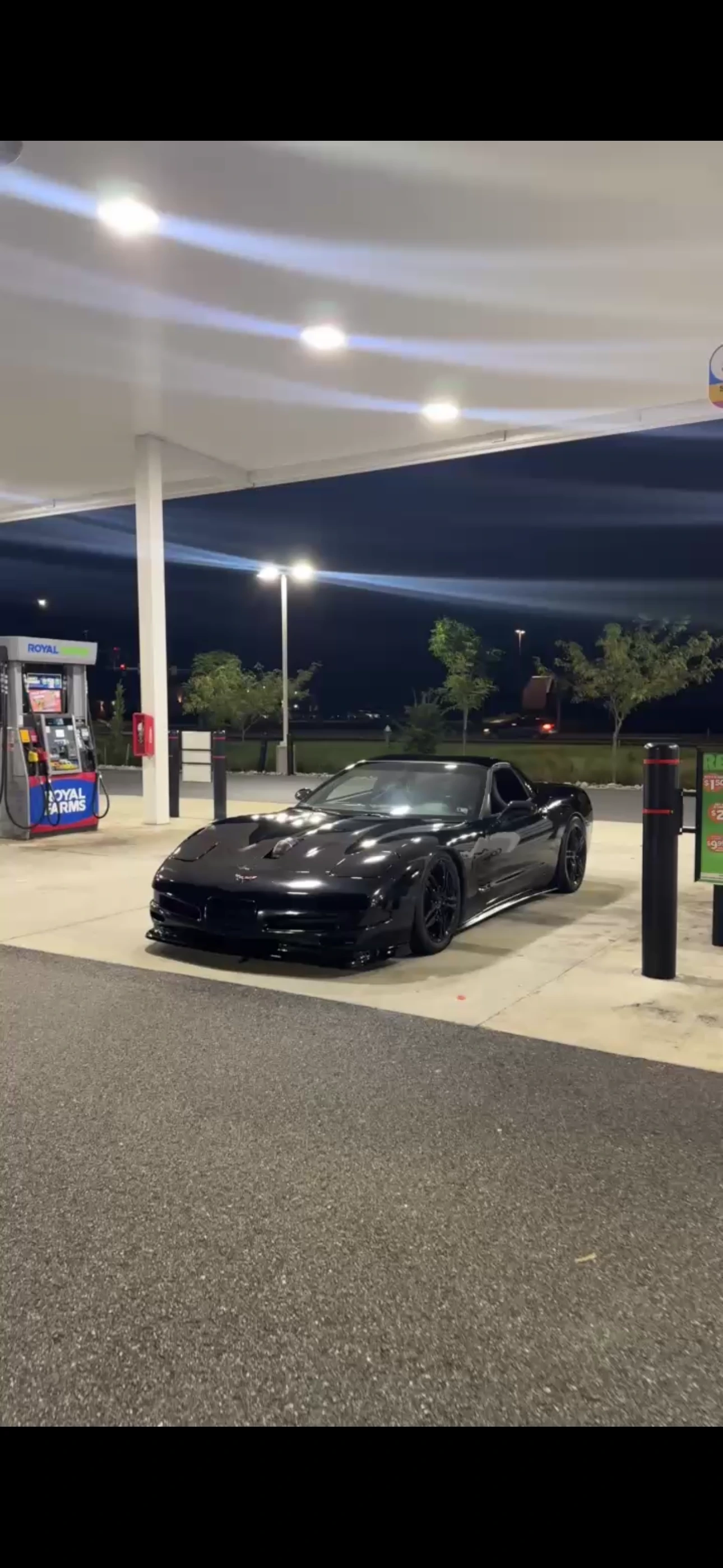 Black Corvette with a vented hood and black wheels, photographed at night