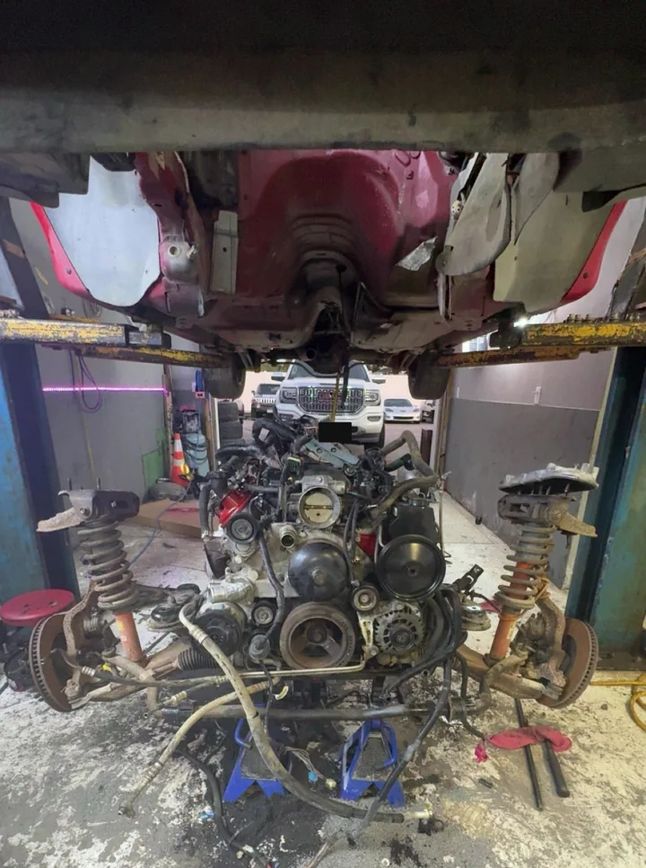 Engine and front suspension beneath a raised red Camaro
